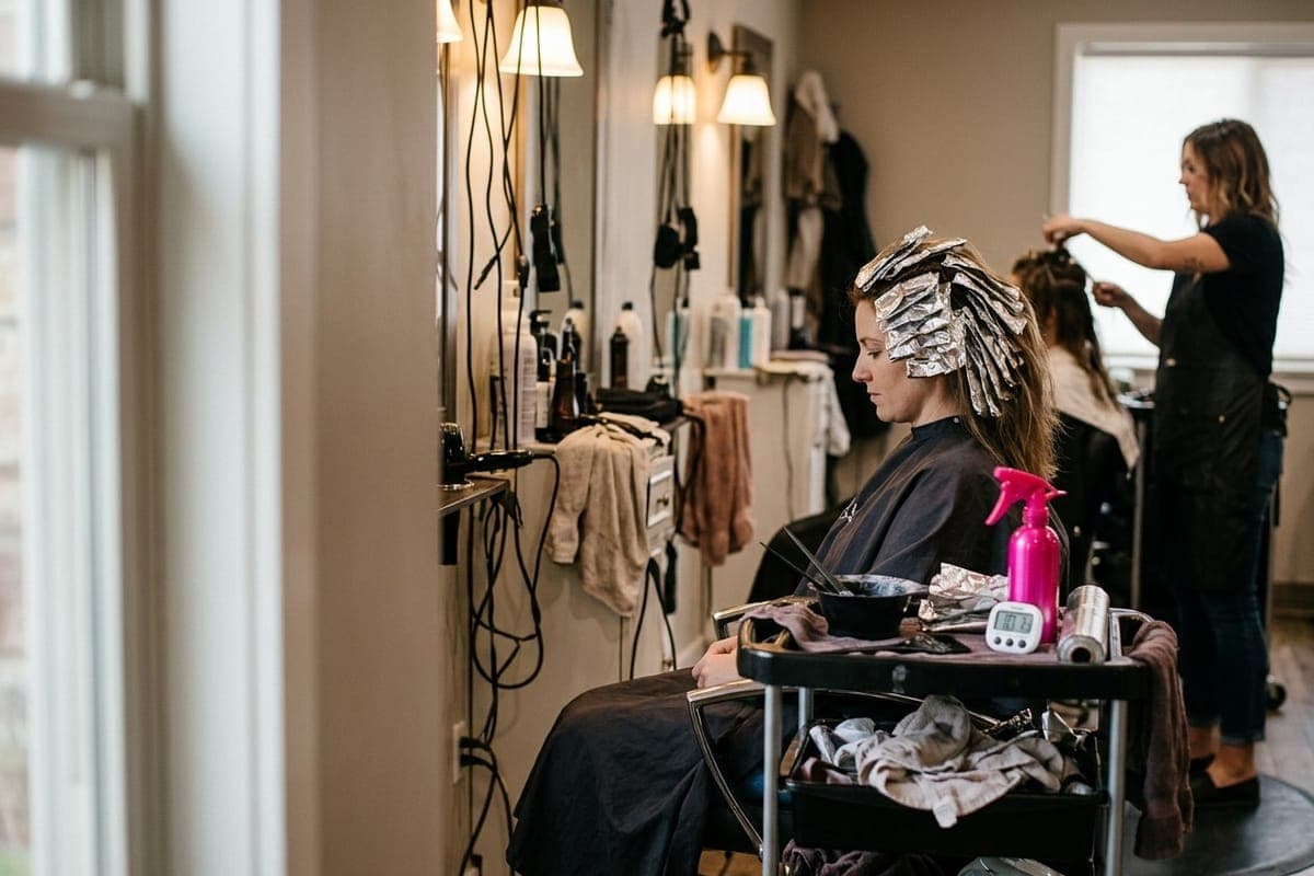 A client sitting with a head of foils while their colour processes, as the colorist works on someone else at the next chair.