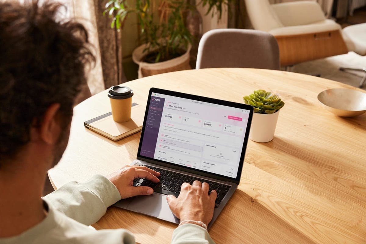 Someone at a table working on a laptop open to a client's record in Inchair.